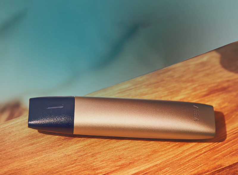 A gold VEEV vape device on a wooden table