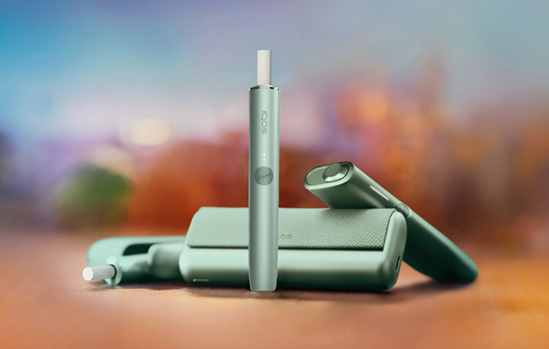 An IQOS ILUMA PRIME device with a TEREA stick inside. Plus, an IQOS ILUMA ONE and IQOS ILUMA device on the side. 