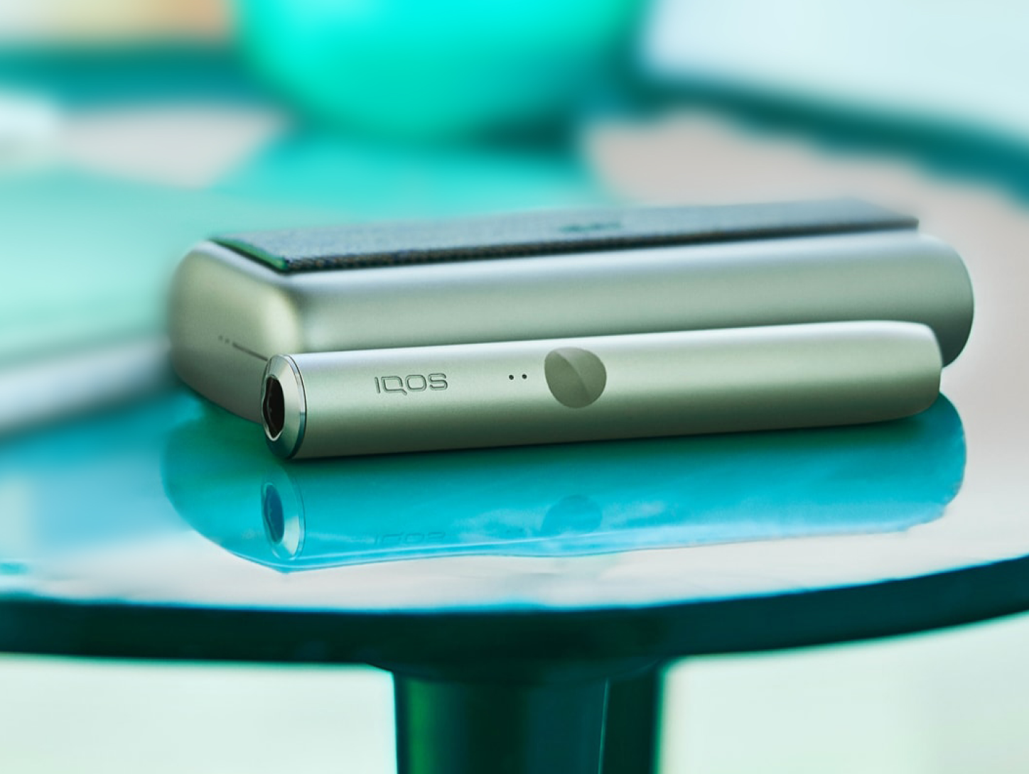 Un appareil IQOS ILUMA vert jade posé sur une table.