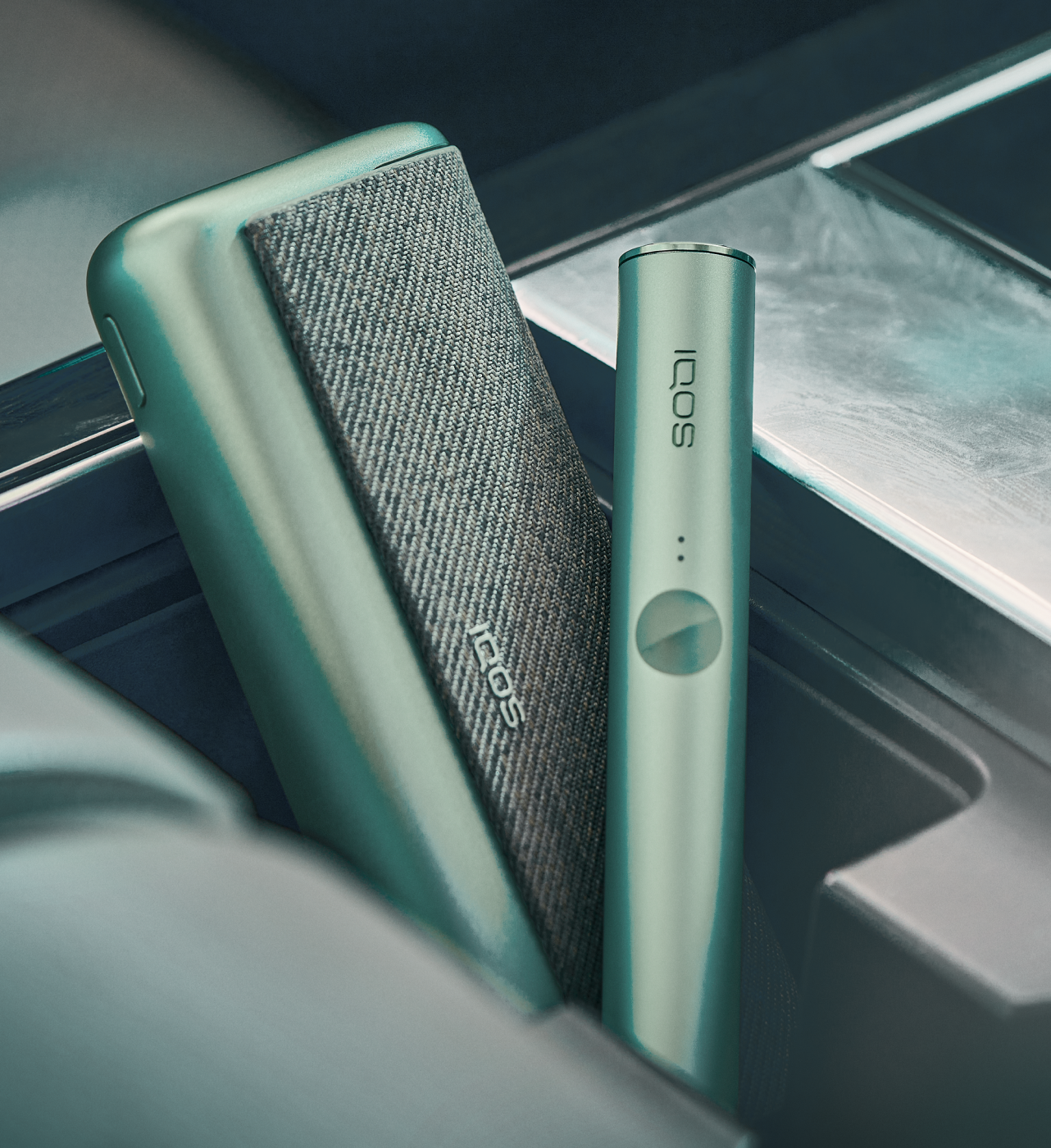 A jade green IQOS ILUMA device sits on a table.