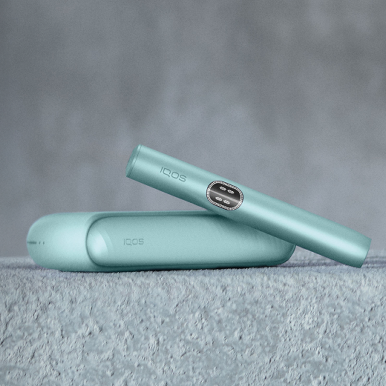 Breeze Blue IQOS ILUMA device in a textrued teal background.  