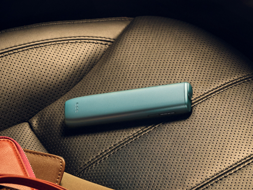 Un appareil IQOS  ILUMA i ONE Bleu Brise posé sur un siège.