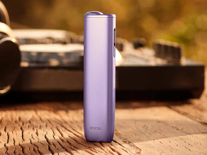 Un appareil IQOS  ILUMA i ONE Violet Digital posé sur un bloc de bois.