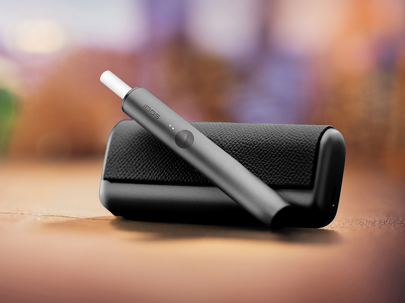Un appareil vert jade IQOS ILUMA PRIME de charge sur une table.