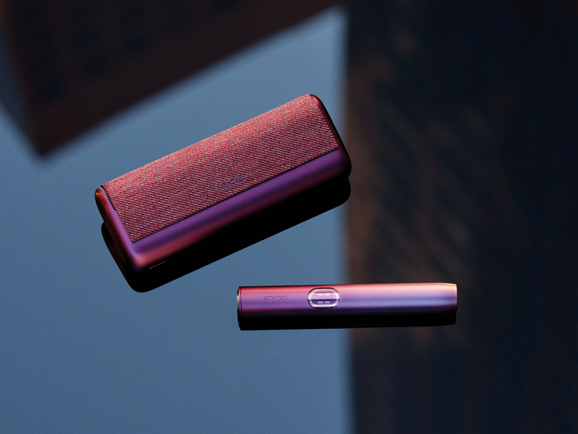 A Garnet Red IQOS ILUMA i PRIME device on a table.