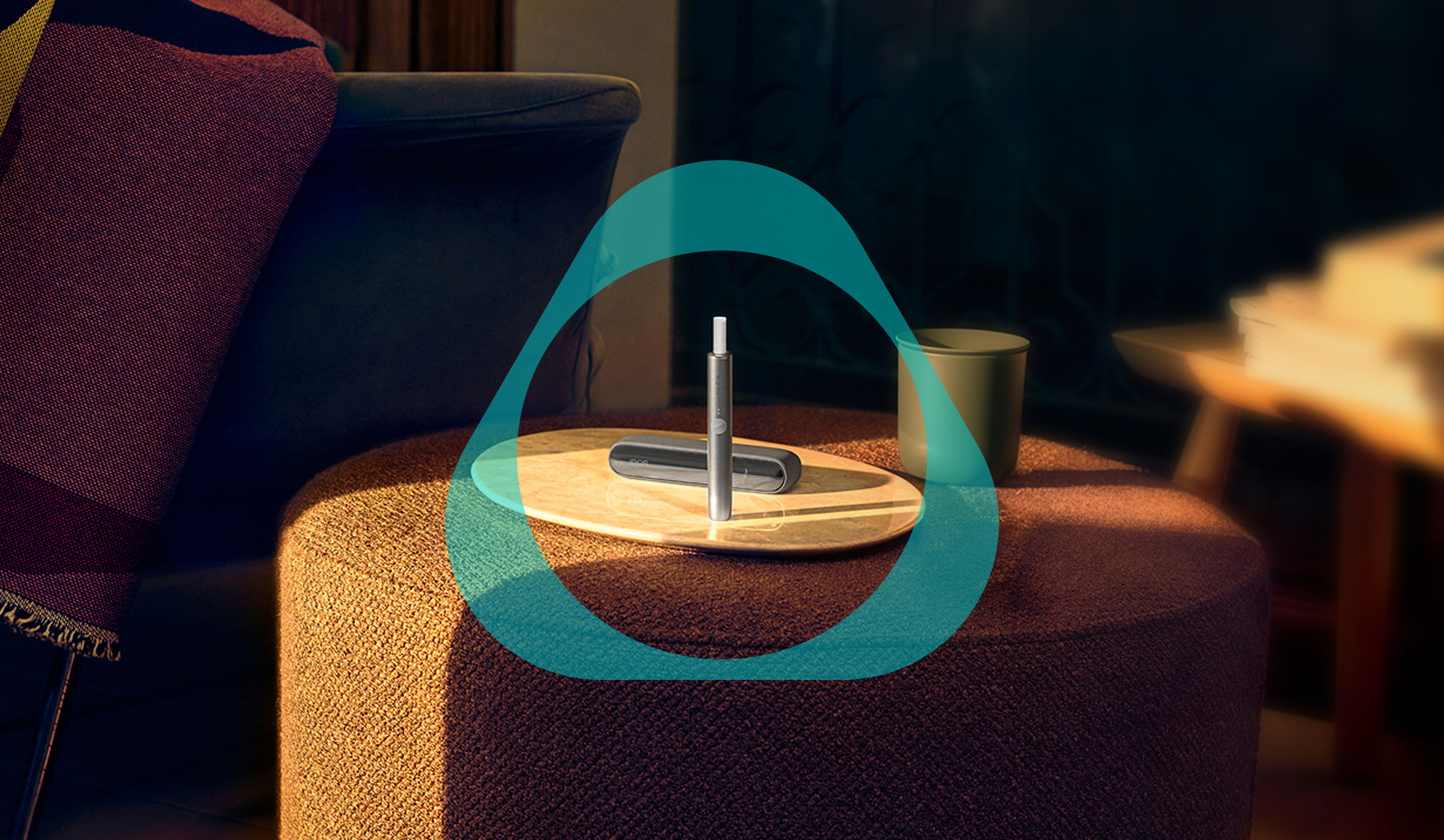 Un appareil IQOS ILUMA avec un bâtonnet TEREA à l’intérieur et un plateau sur une ottomane. 