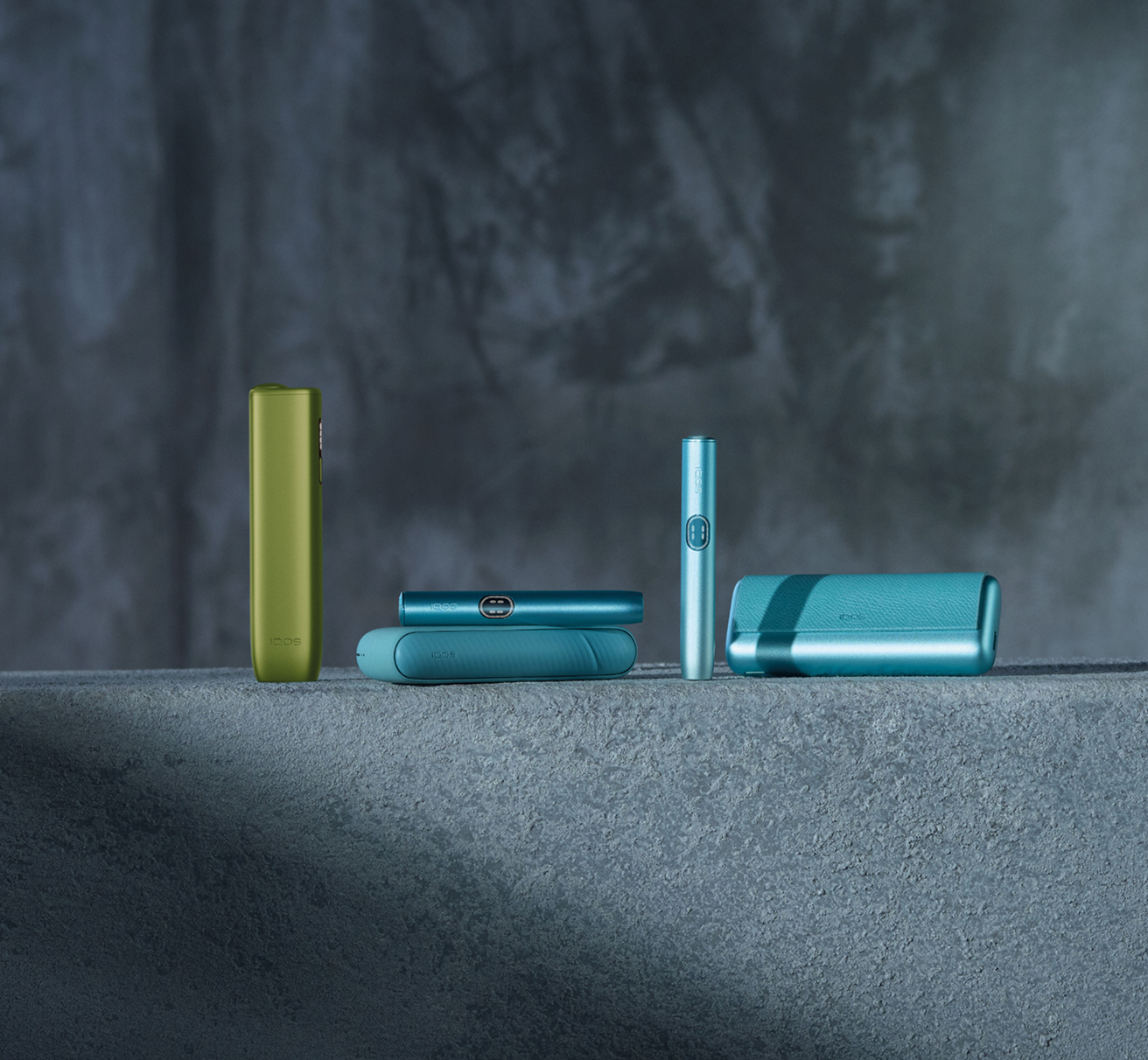 An IQOS ILUMA device on a rock next to an outdoor bag.