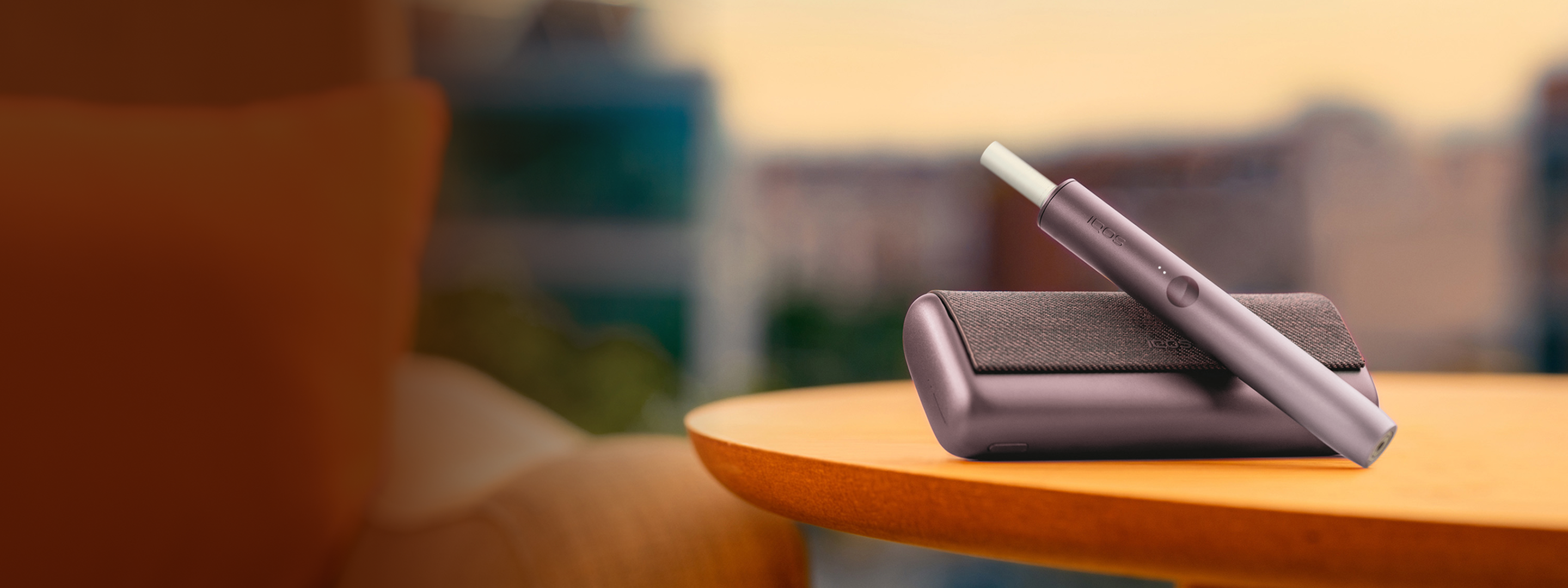 An IQOS ILUMA PRIME with a TEREA stick inside on a wooden table. 