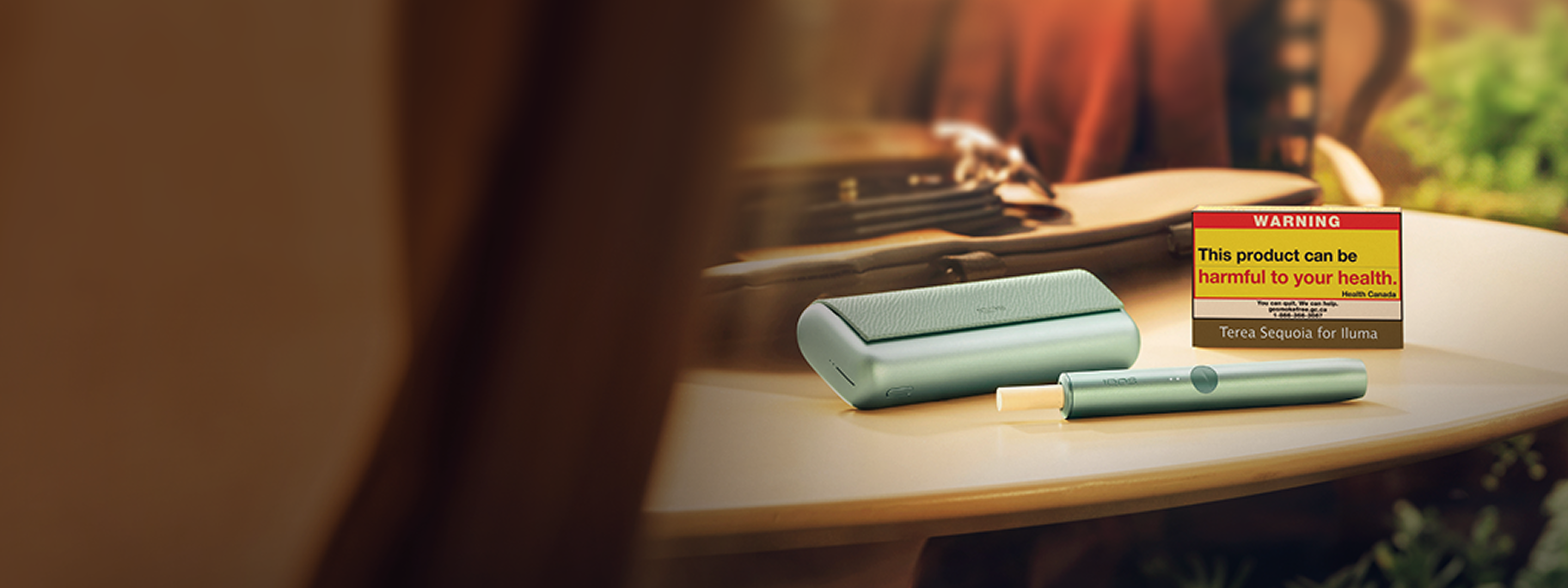 Un appareil IQOS ILUMA PRIME avec un bâtonnet TEREA à l’intérieur à côté d’un paquet TEREA sur une table.