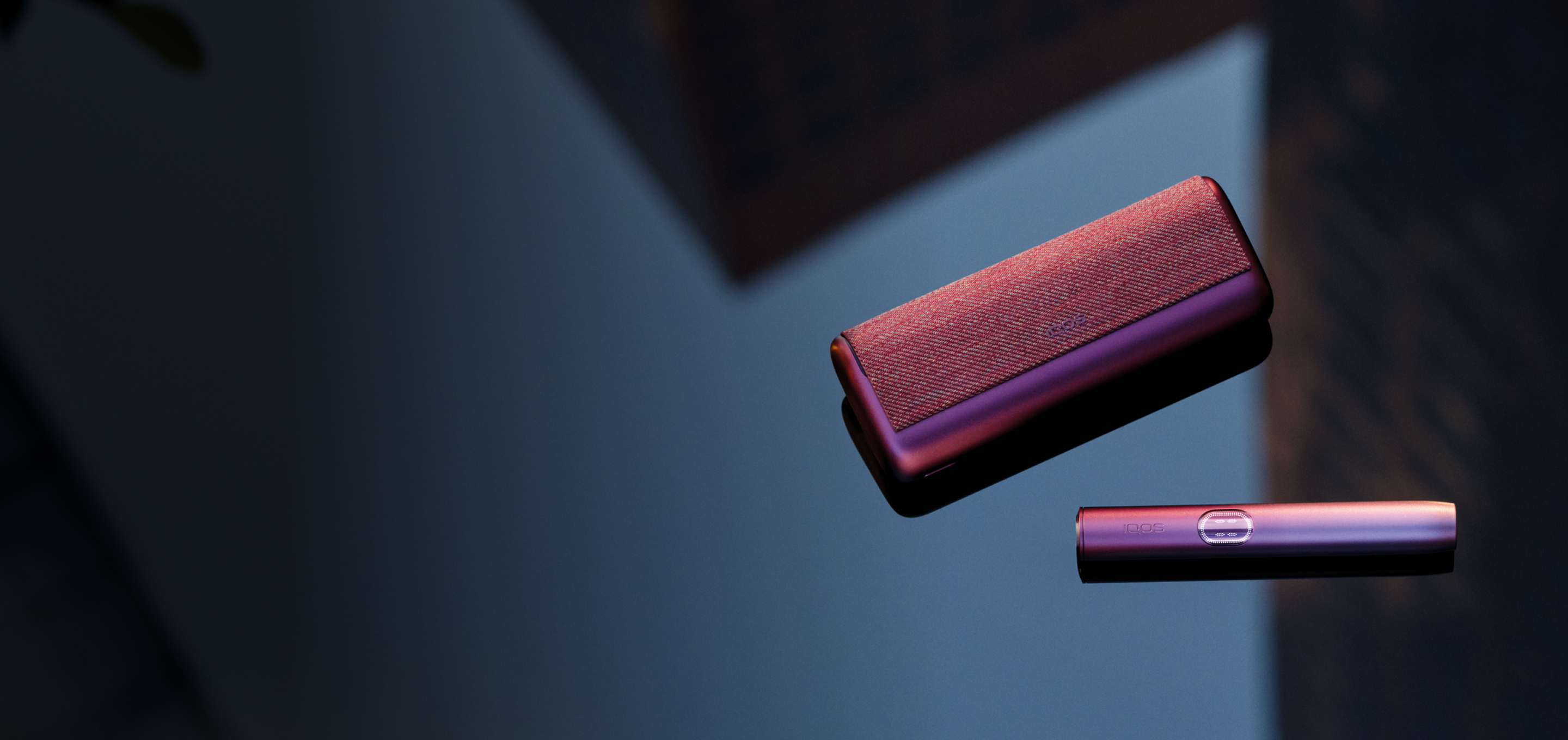 A Garnet Red IQOS ILUMA i PRIME on a table. 