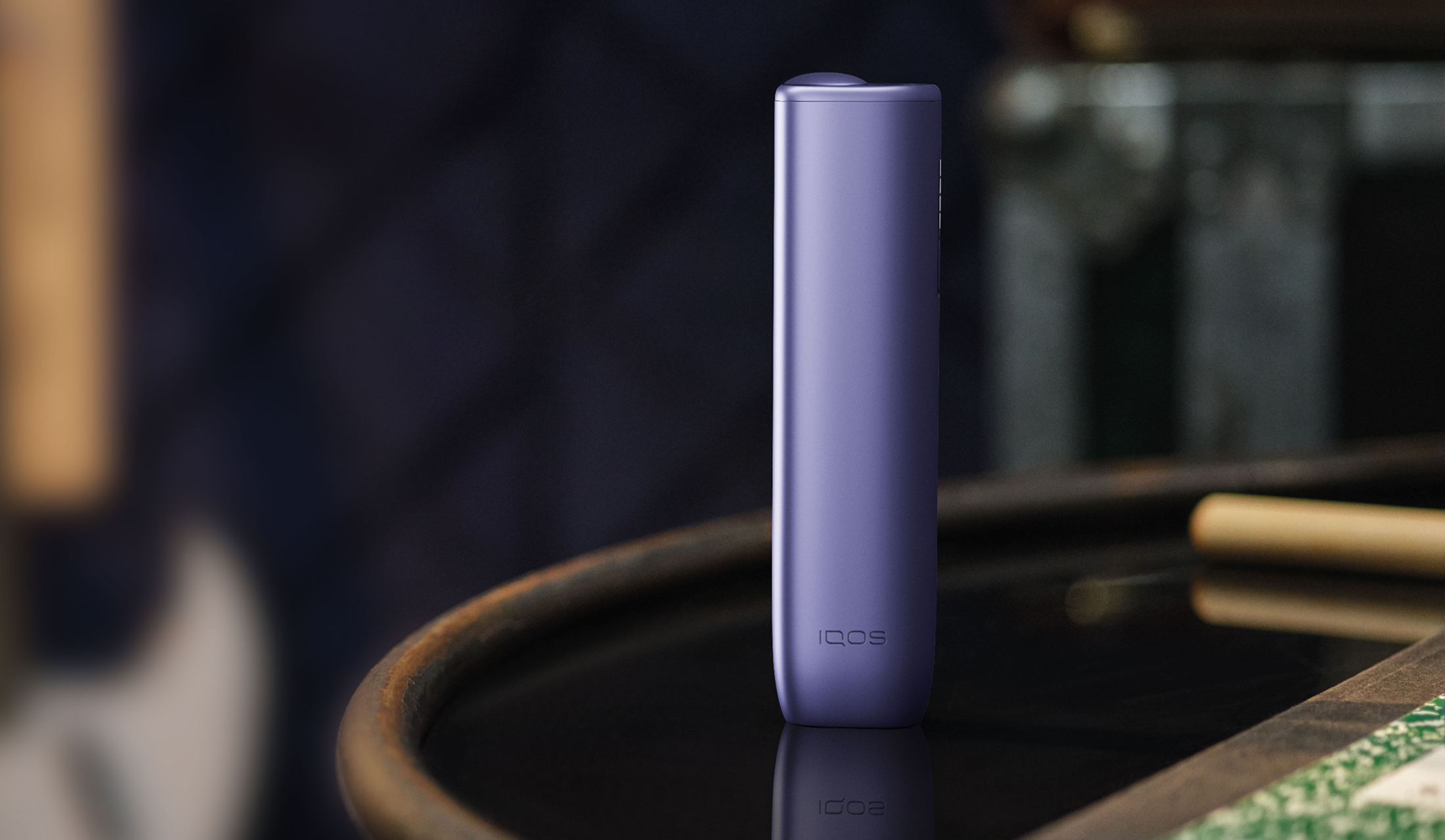 A Digital Violet IQOS ILUMA i ONE device on a table. 