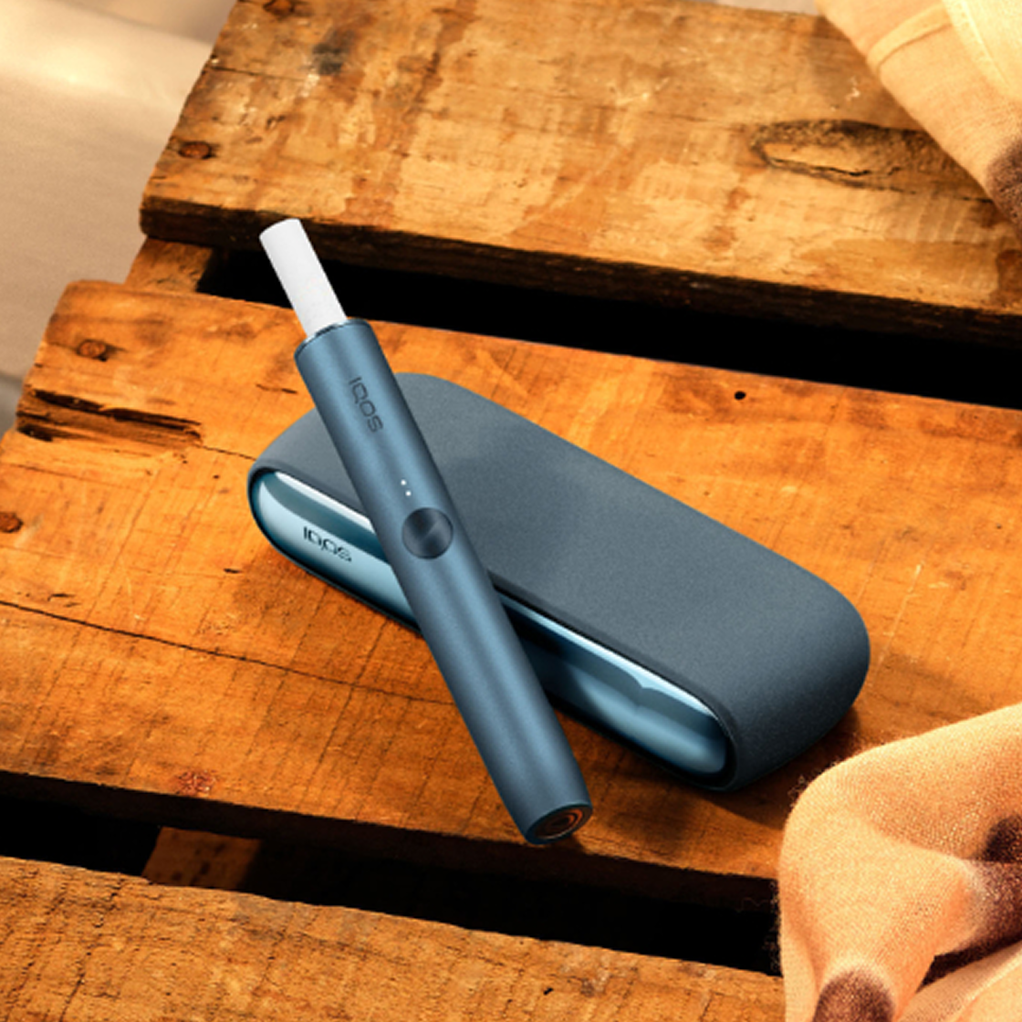 Un appareil IQOS ILUMA dans un poste de charge avec un chargeur de poche sur une table.