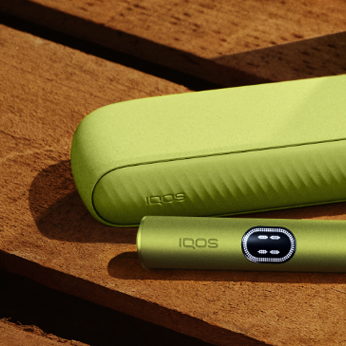 A Leaf Green IQOS ILUMA i device on a wooden table.