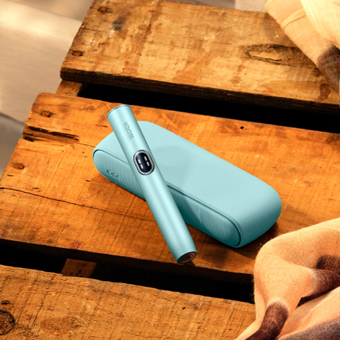 A Blue Breeze IQOS ILUMA i device on a wooden table. 