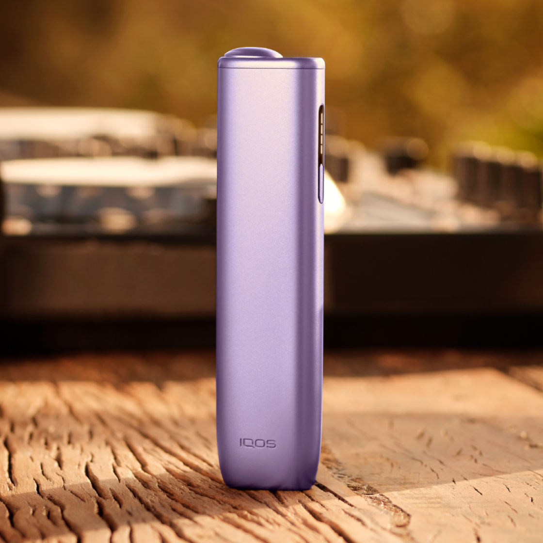 A Digital Violet IQOS ILUMA i ONE device standing up on a wooden block. 
