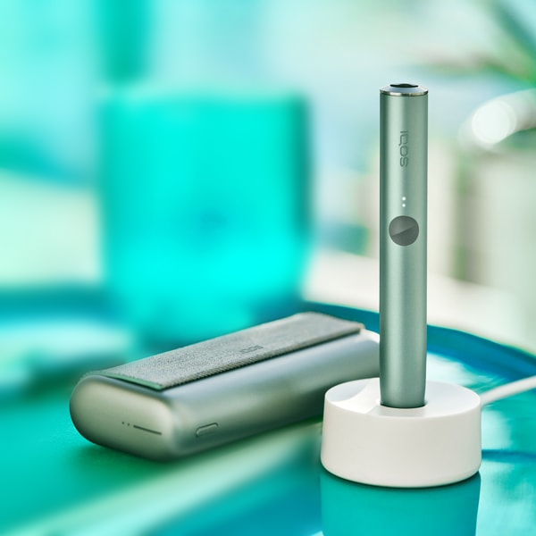 A Jade Green IQOS ILUMA PRIME Holder in a charging station.