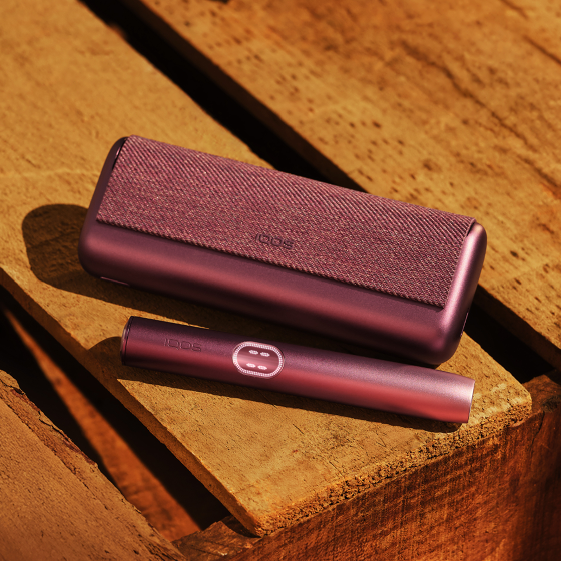 A Midnight Black IQOS ILUMA i PRIME device on a wooden table. 