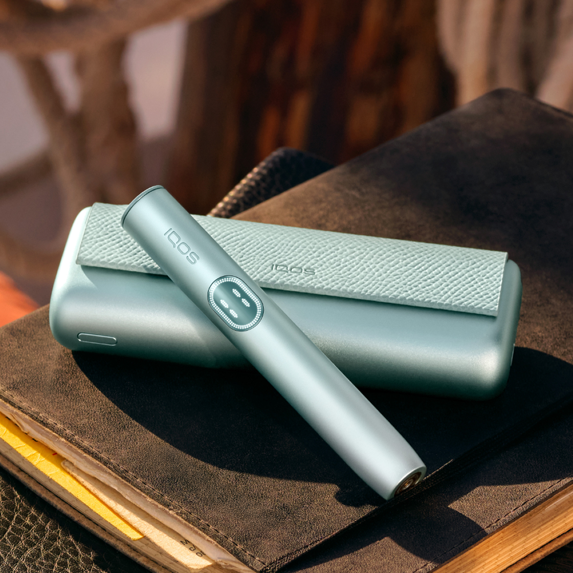 A Breeze Blue IQOS ILUMA i PRIME device on a book.