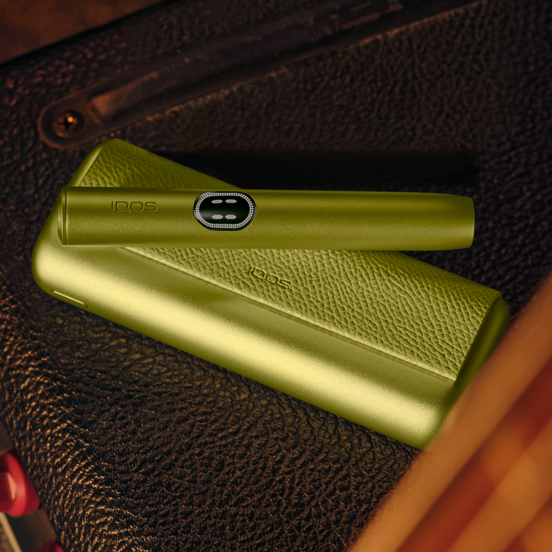 A Leaf Green IQOS ILUMA i PRIME device on a leather surface.