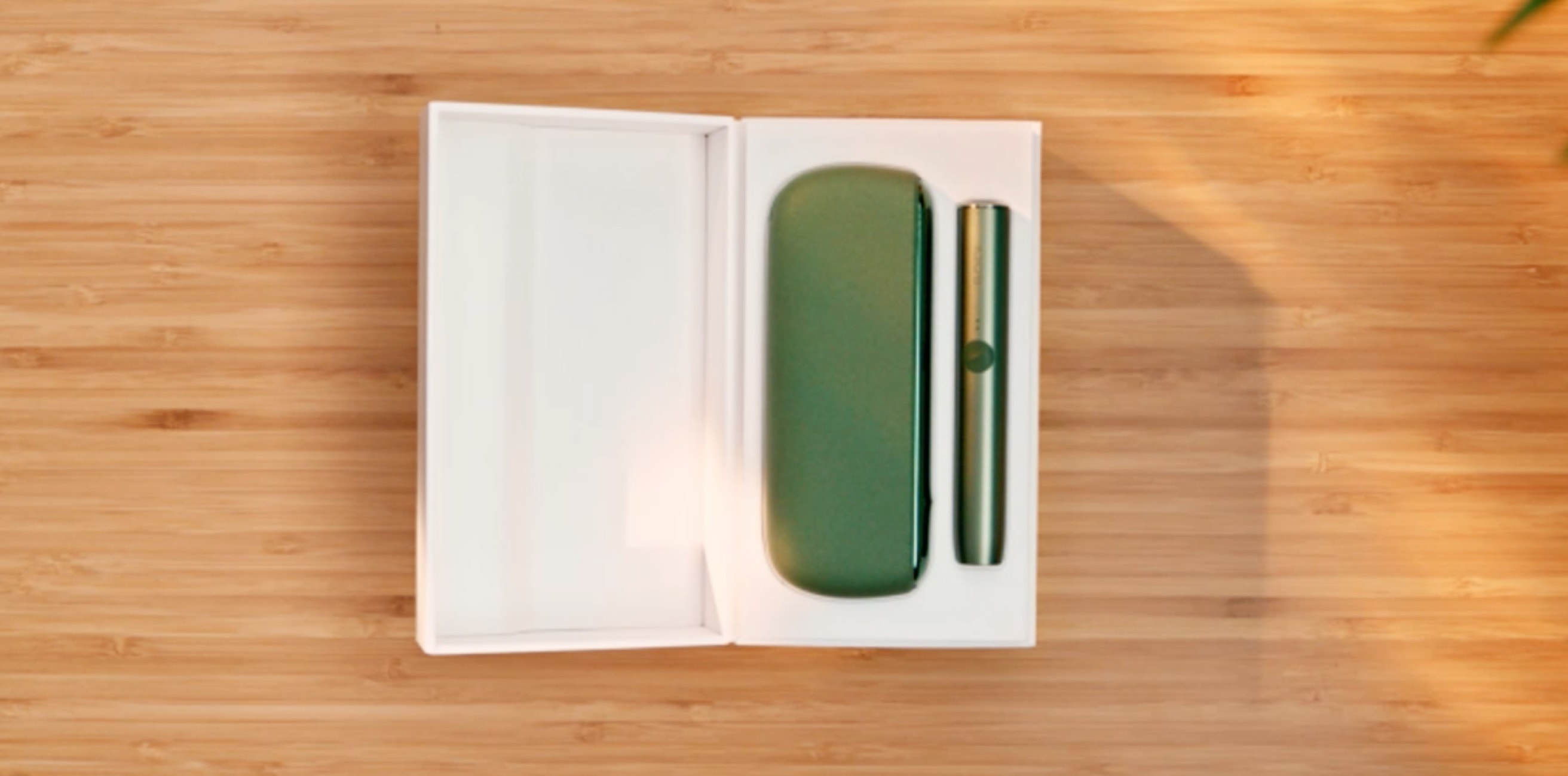 Un support vert mousse et un chargeur de poche pour IQOS ILUMA dans une boîte.