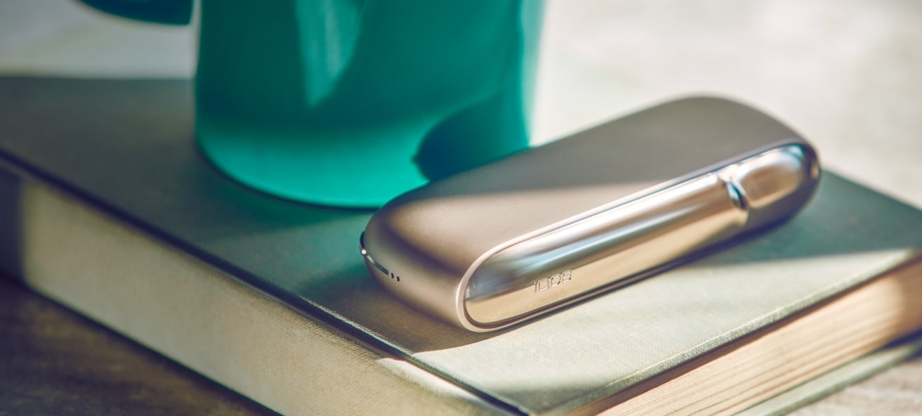 A gold IQOS device on a book.
