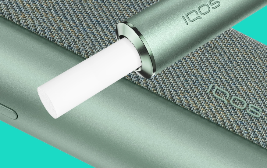 A jade green IQOS ILUMA PRIME holder and pocket charger.